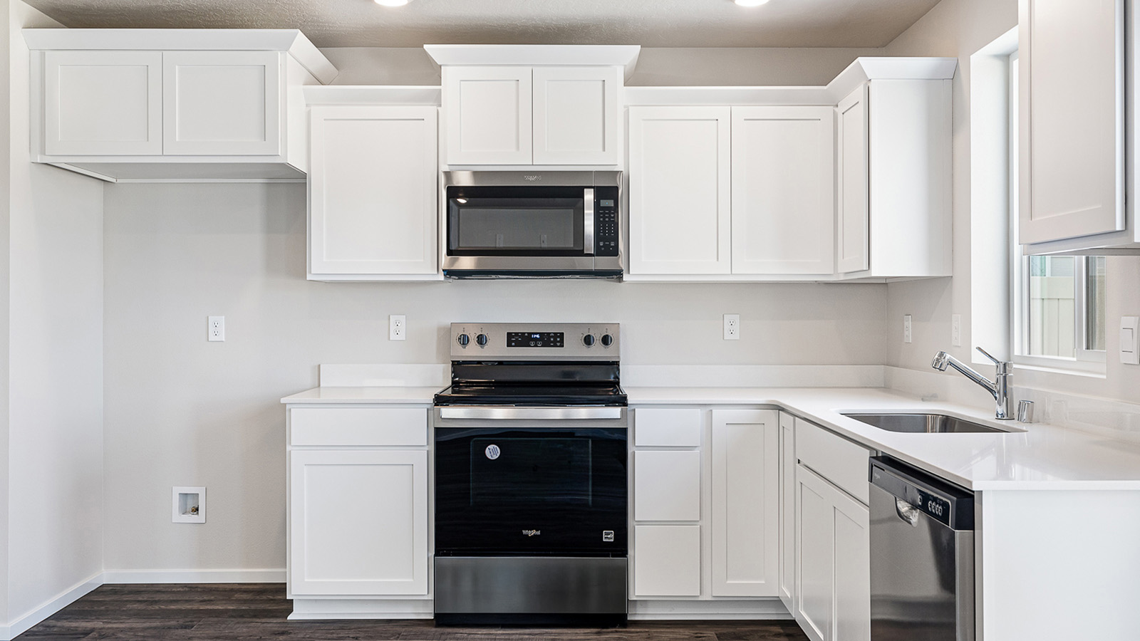 L-shaped kitchen with shaker cabinets, quartz counters, stainless steel appliances, and a pantry