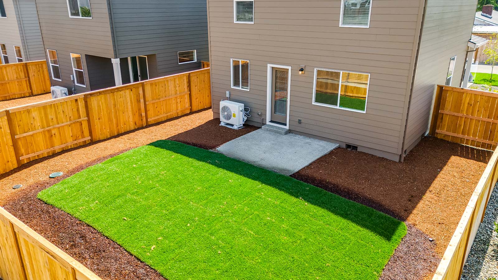 fully fenced backyard with sod lawn and a patio