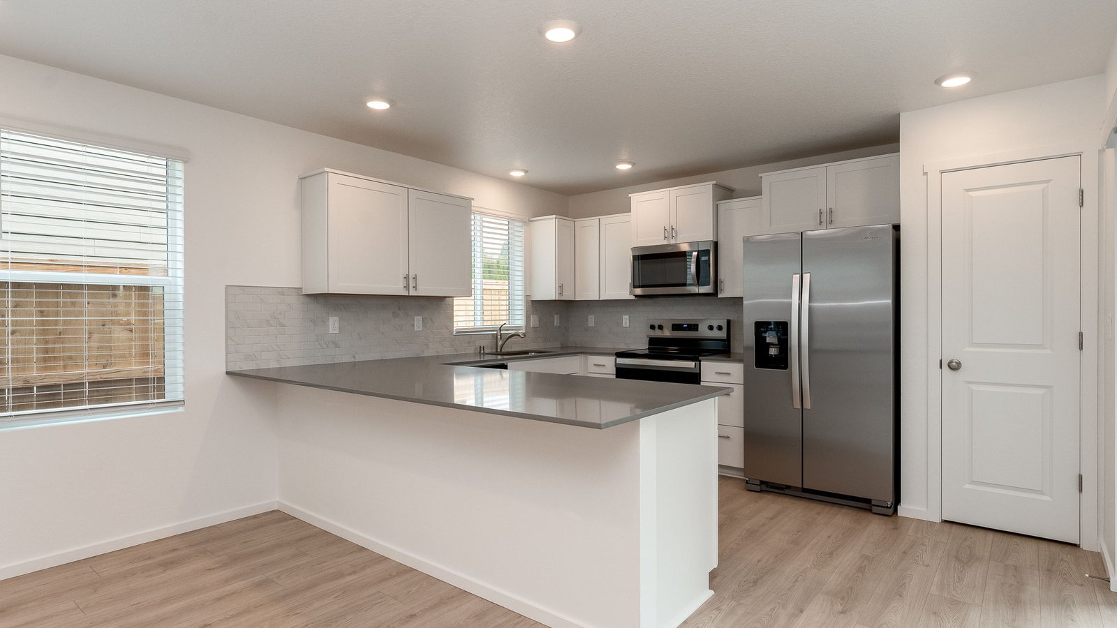 U-shaped kitchen with shaker cabinets, quartz counters, stainless steel appliances, pantry, and a breakfast bar