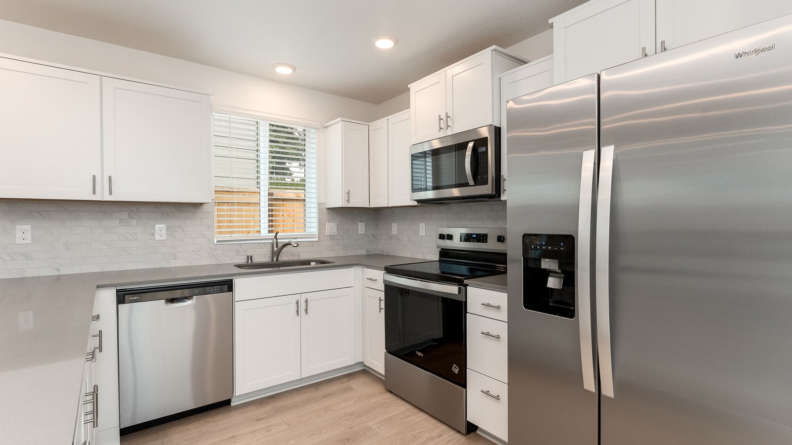 U-shaped kitchen with shaker cabinets, quartz counters, stainless steel appliances, pantry, and a breakfast bar