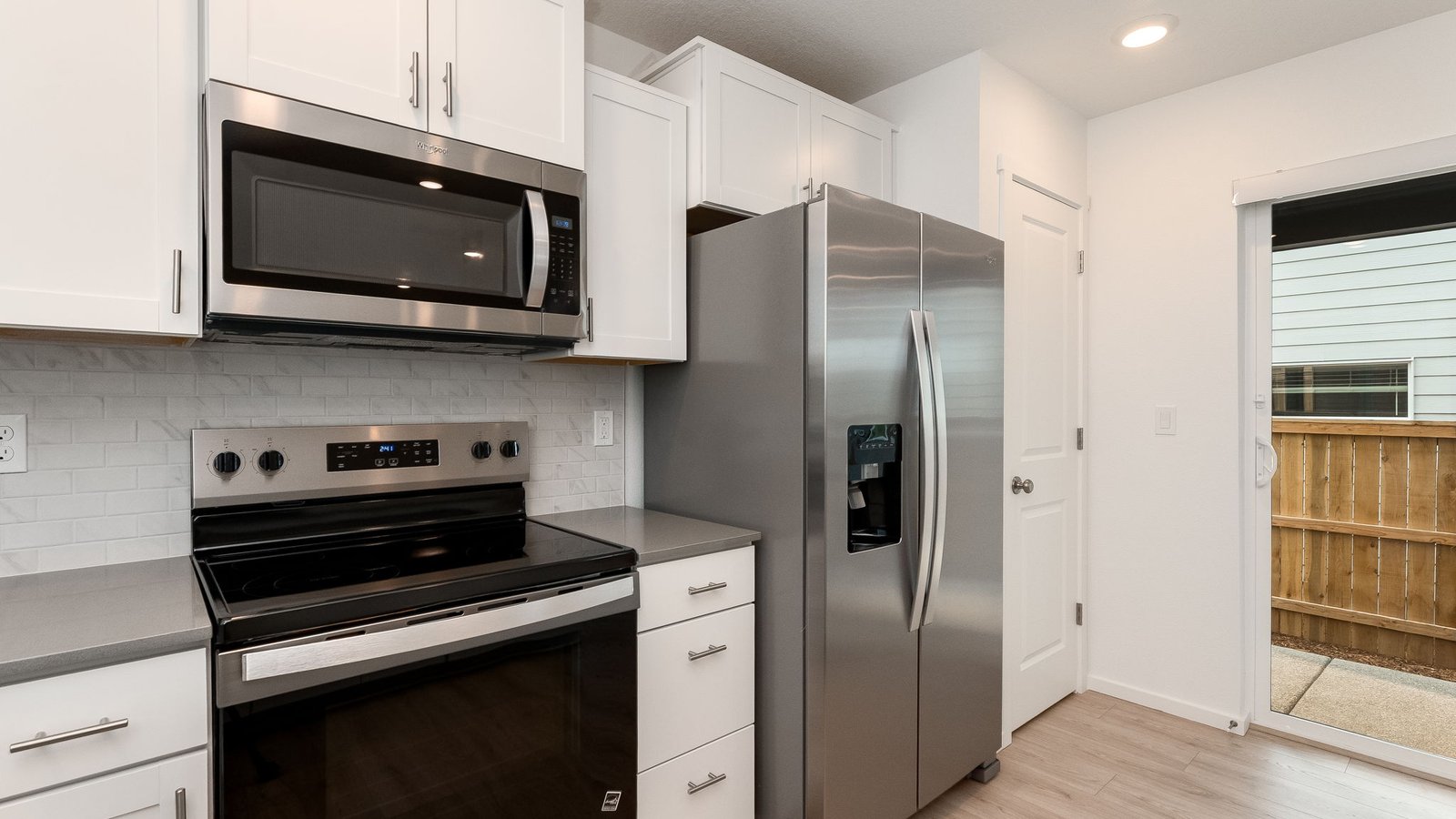 U-shaped kitchen with shaker cabinets, quartz counters, stainless steel appliances, pantry, and a breakfast bar