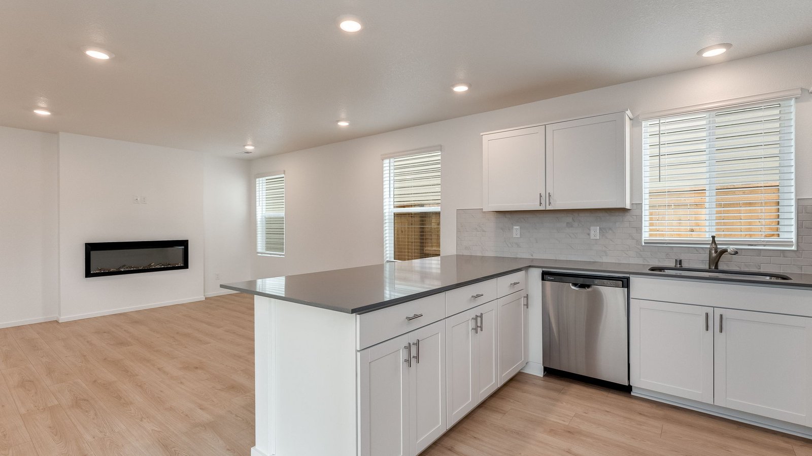 U-shaped kitchen with shaker cabinets, quartz counters, stainless steel appliances, pantry, and a breakfast bar