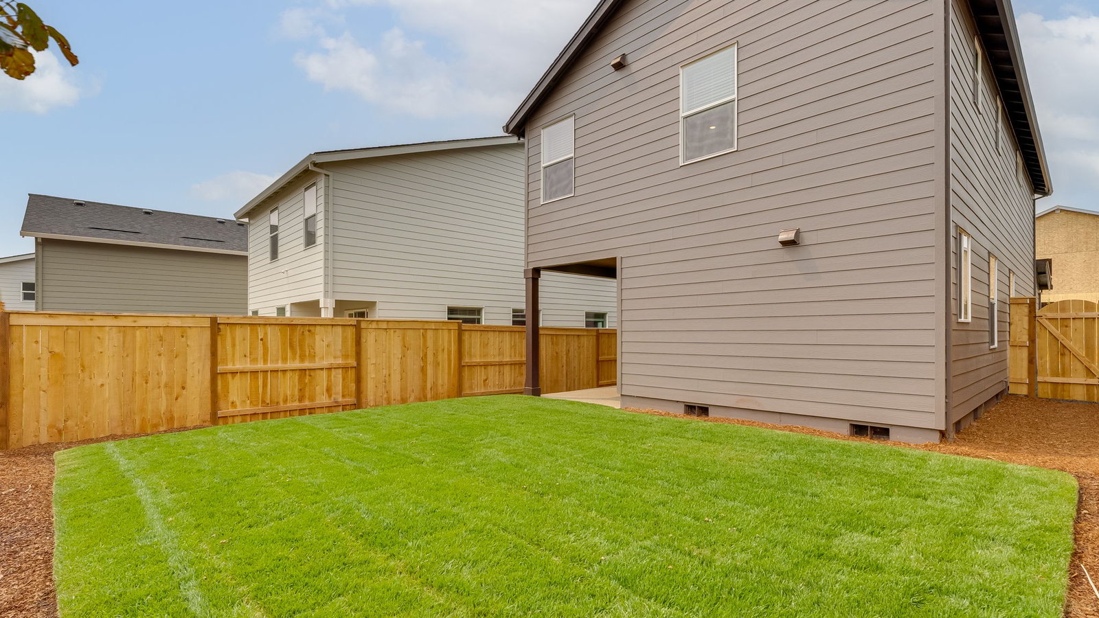 fully fenced backyard with sod lawn and a patio