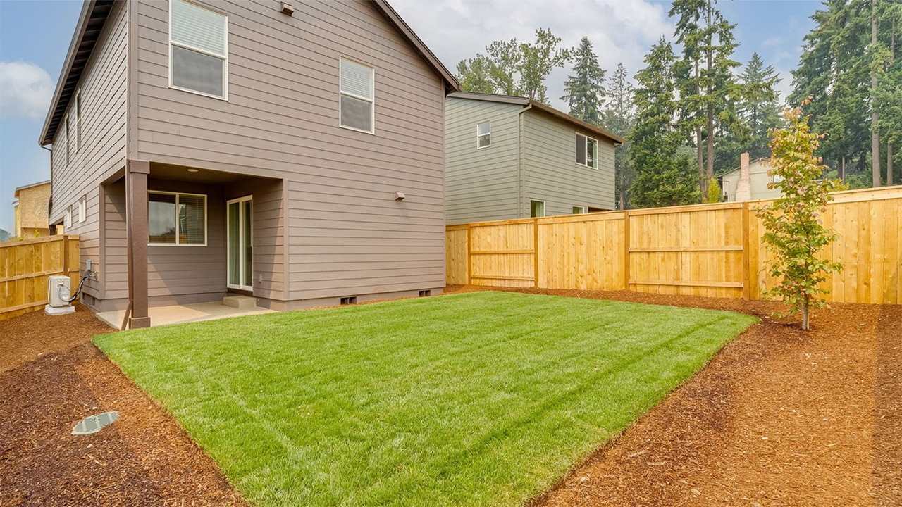 fully fenced backyard with sod lawn and a patio