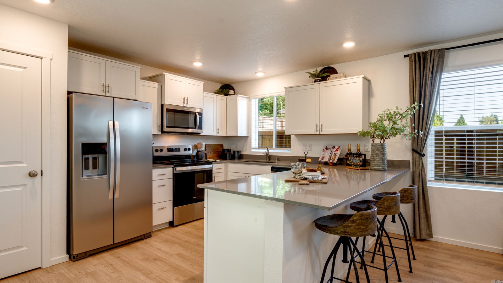 U-shaped kitchen with shaker cabinets, quartz counters, stainless steel appliances, pantry, and a breakfast bar