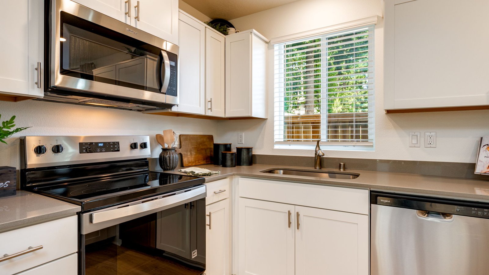 U-shaped kitchen with shaker cabinets, quartz counters, stainless steel appliances, pantry, and a breakfast bar