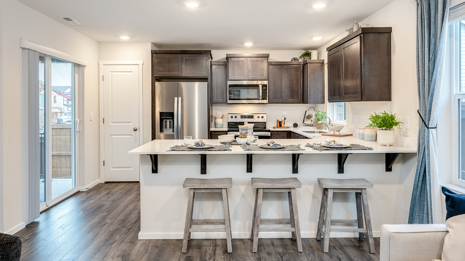 U-shaped kitchen with shaker cabinets, quartz counters, stainless steel appliances, pantry, and a breakfast bar