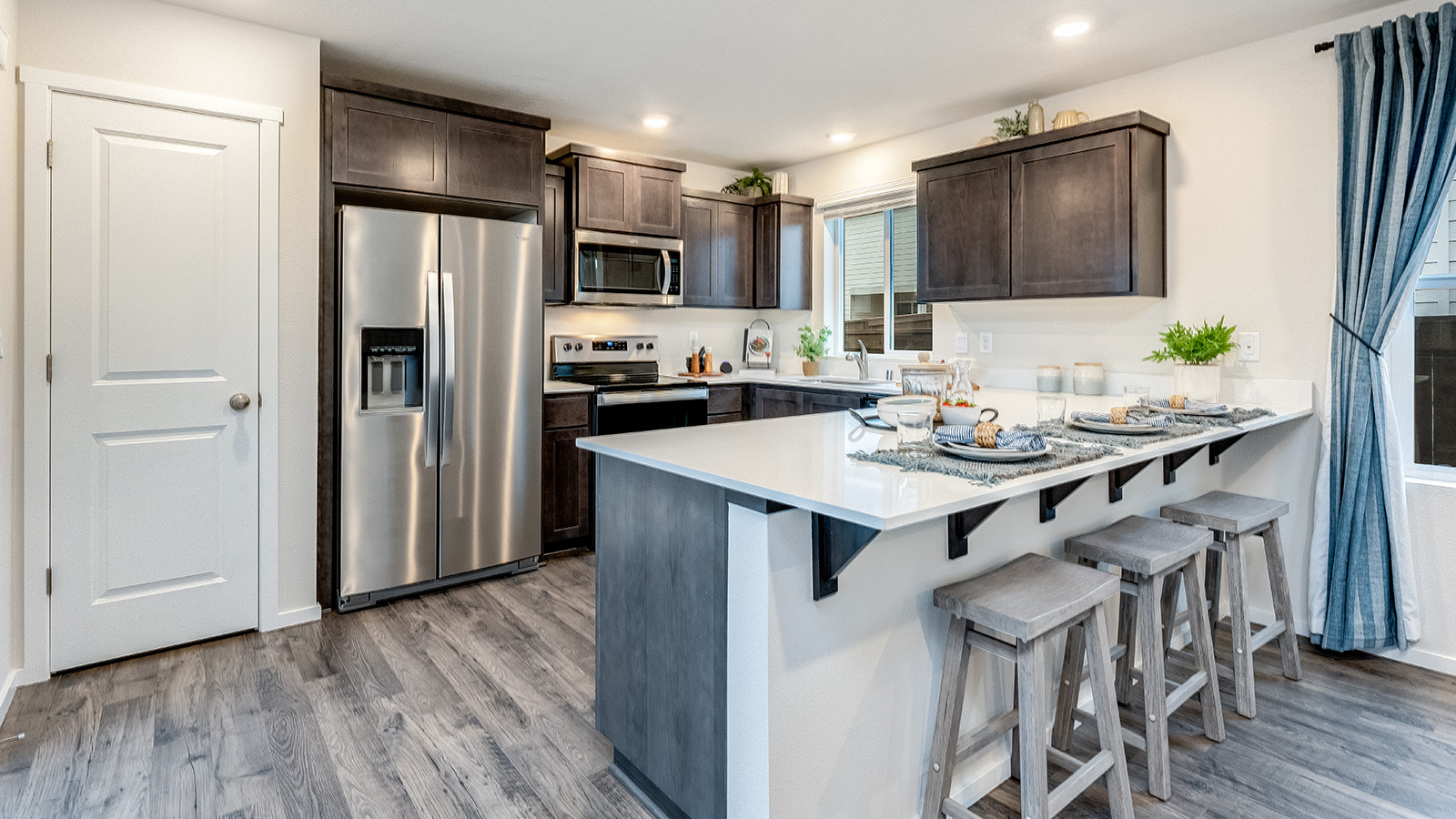 U-shaped kitchen with shaker cabinets, quartz counters, stainless steel appliances, pantry, and a breakfast bar