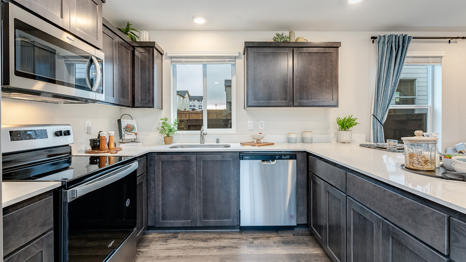 U-shaped kitchen with shaker cabinets, quartz counters, stainless steel appliances, pantry, and a breakfast bar