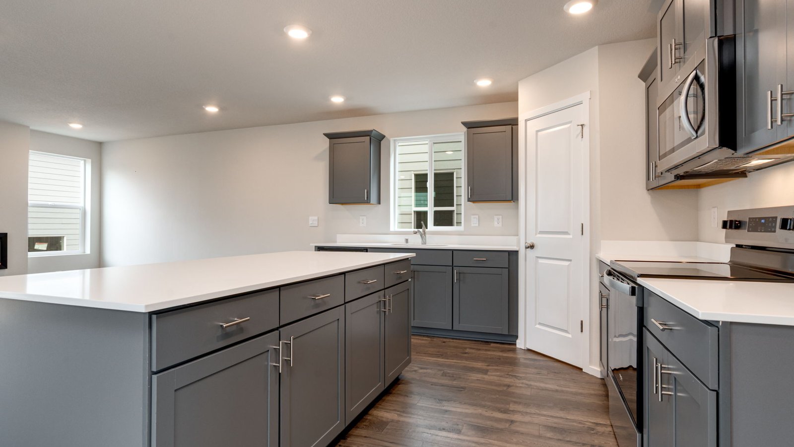 Kitchen with shaker cabinets, quartz counters, stainless steel appliances, pantry, and an island with a breakfast bar