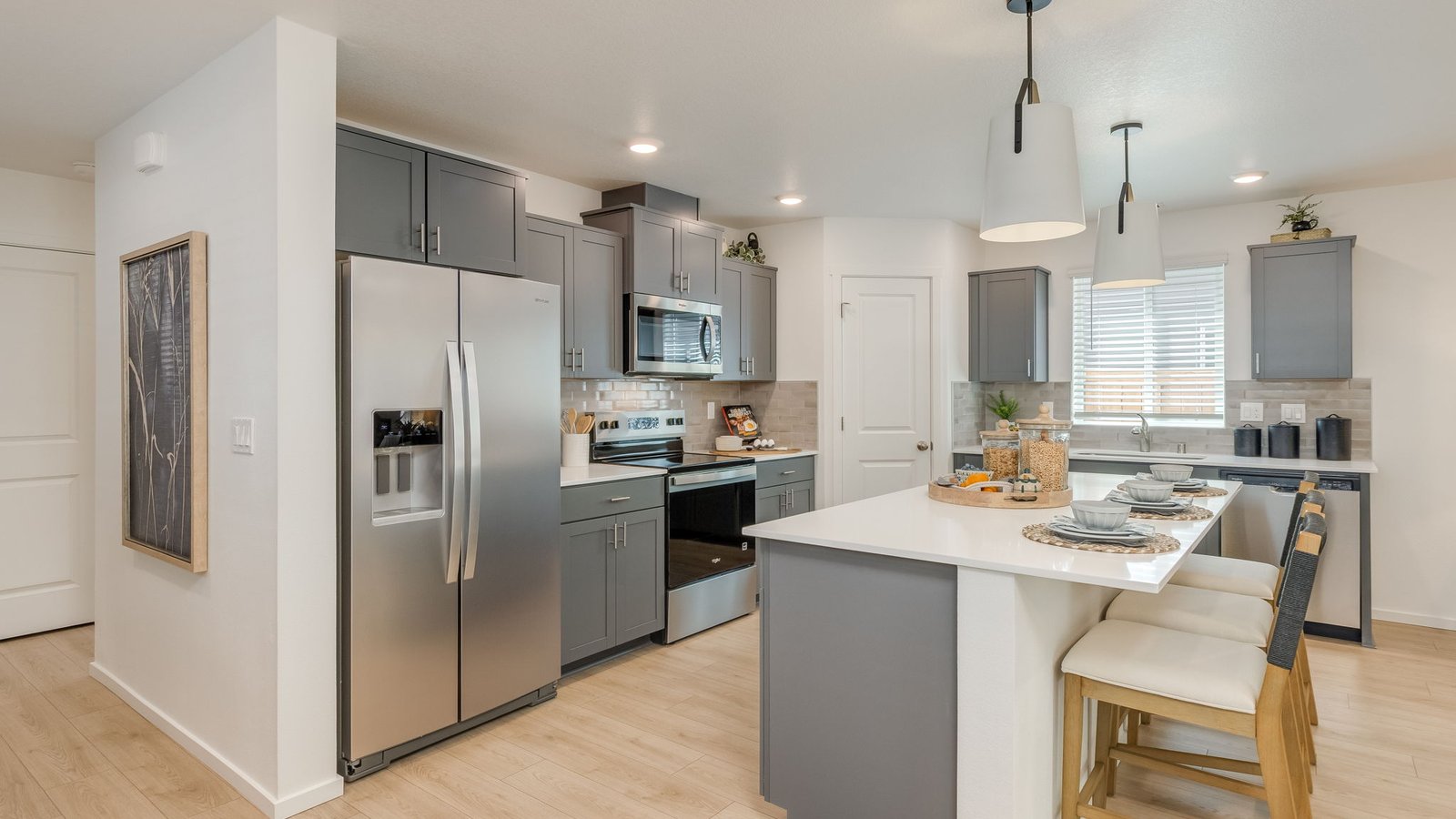 Kitchen with shaker cabinets, quartz counters, stainless steel appliances, pantry, and an island with a breakfast bar