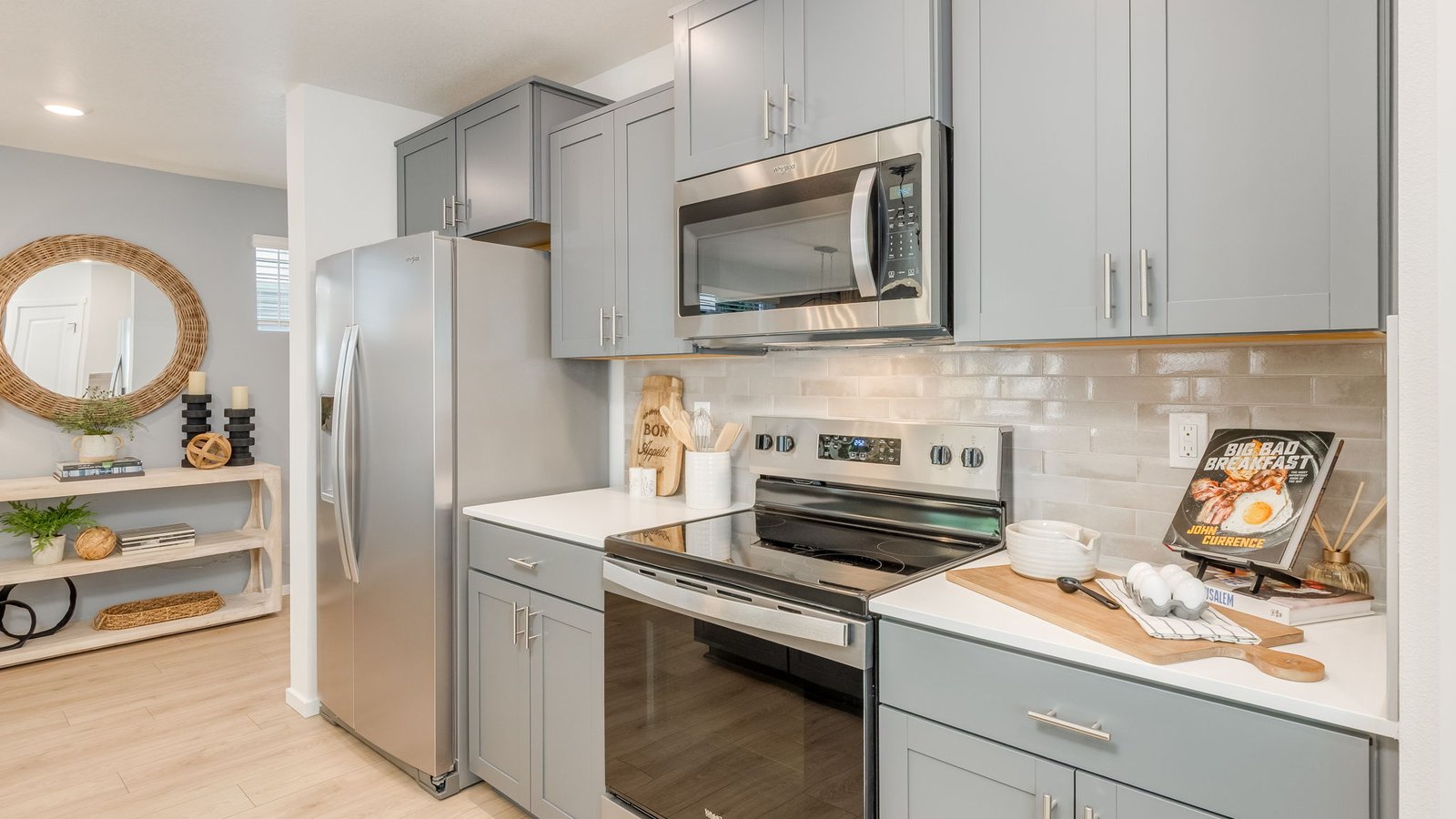 Kitchen with shaker cabinets, quartz counters, stainless steel appliances, pantry, and an island with a breakfast bar