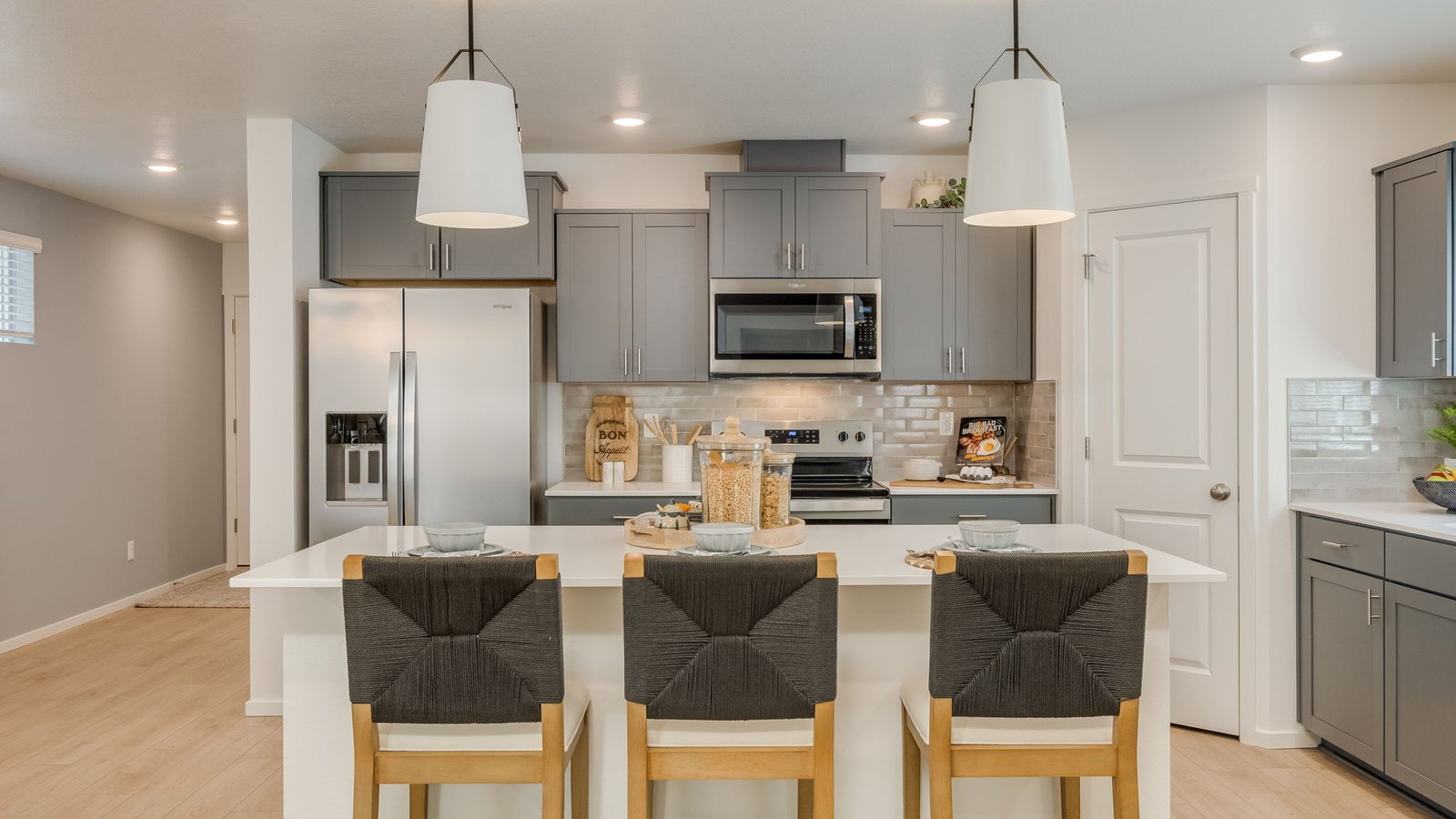 Kitchen with shaker cabinets, quartz counters, stainless steel appliances, pantry, and an island with a breakfast bar
