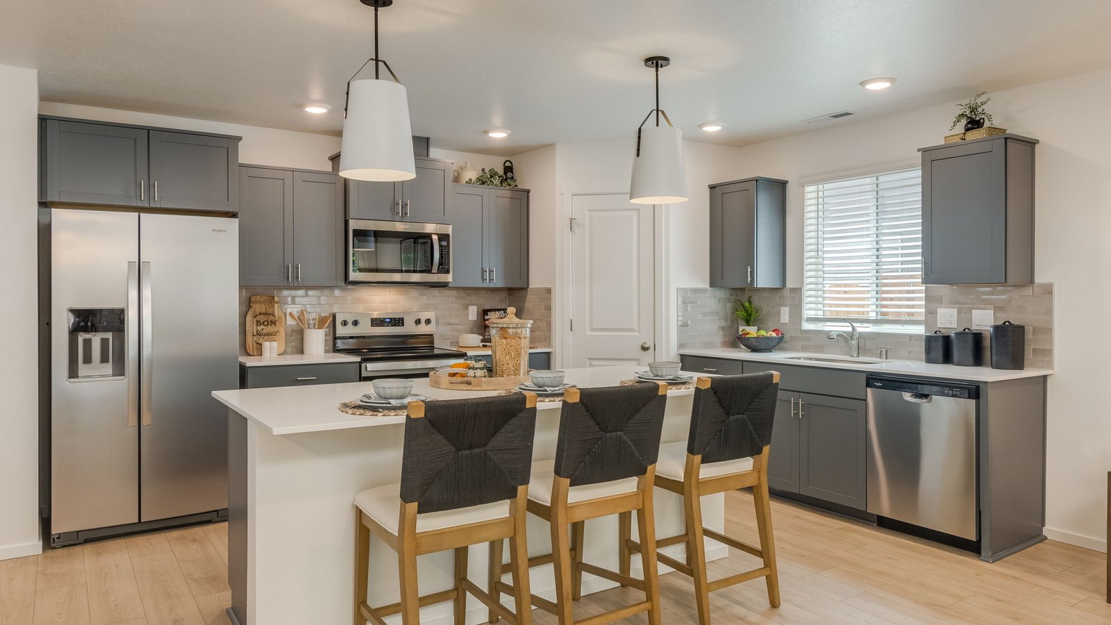 Kitchen with shaker cabinets, quartz counters, stainless steel appliances, pantry, and an island with a breakfast bar