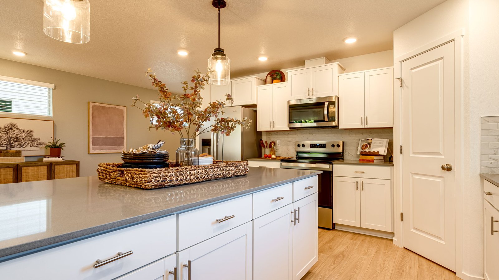 Kitchen with shaker cabinets, quartz counters, stainless steel appliances, pantry, and an island with a breakfast bar