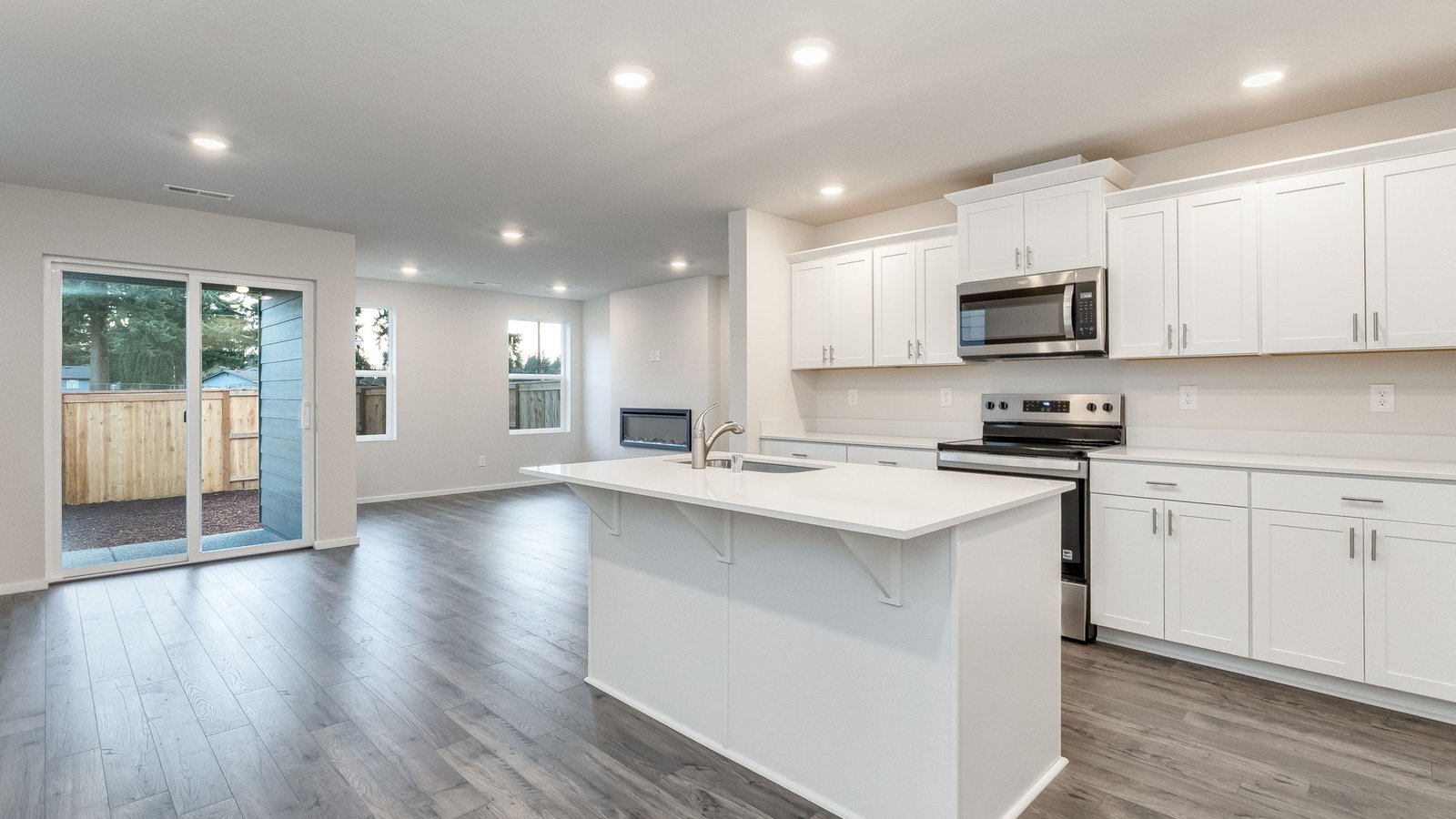 Kitchen with shaker cabinets, quartz counters, stainless steel appliances, pantry, and an island with a breakfast bar