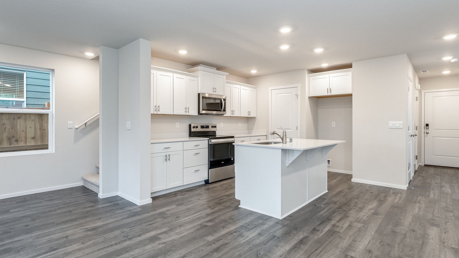 Kitchen with shaker cabinets, quartz counters, stainless steel appliances, pantry, and an island with a breakfast bar