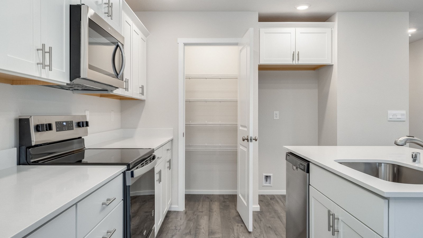 Kitchen with shaker cabinets, quartz counters, stainless steel appliances, pantry, and an island with a breakfast bar
