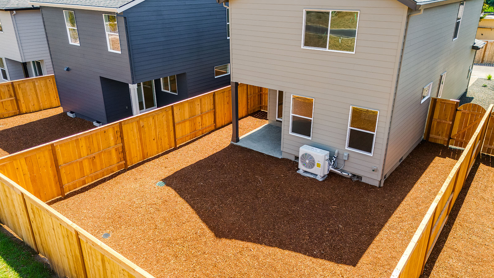 fully fenced backyard with bark chips and a patio