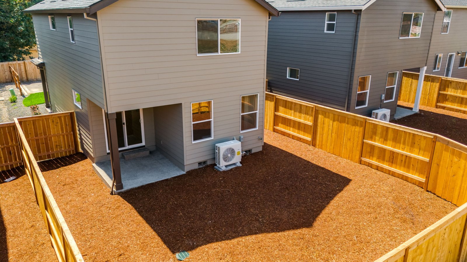 fully fenced backyard with bark chips and a patio