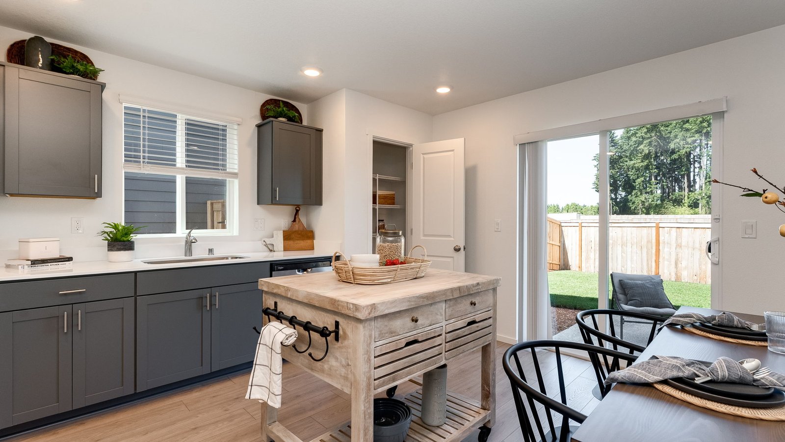 L-shaped kitchen with shaker cabinets, quartz counters, stainless steel appliances, and a pantry