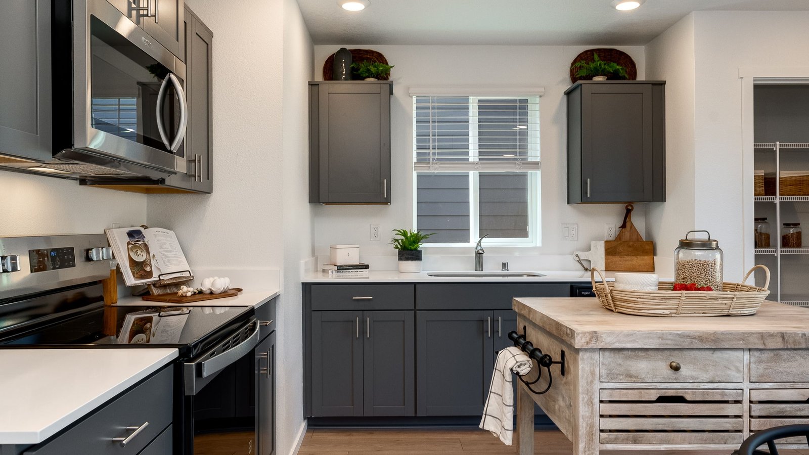 L-shaped kitchen with shaker cabinets, quartz counters, stainless steel appliances, and a pantry