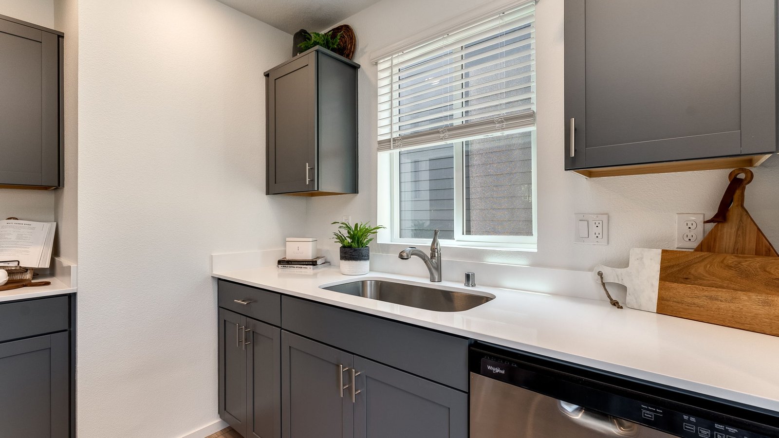 L-shaped kitchen with shaker cabinets, quartz counters, stainless steel appliances, and a pantry
