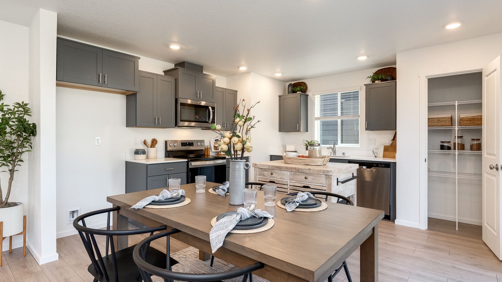 L-shaped kitchen with shaker cabinets, quartz counters, stainless steel appliances, and a pantry