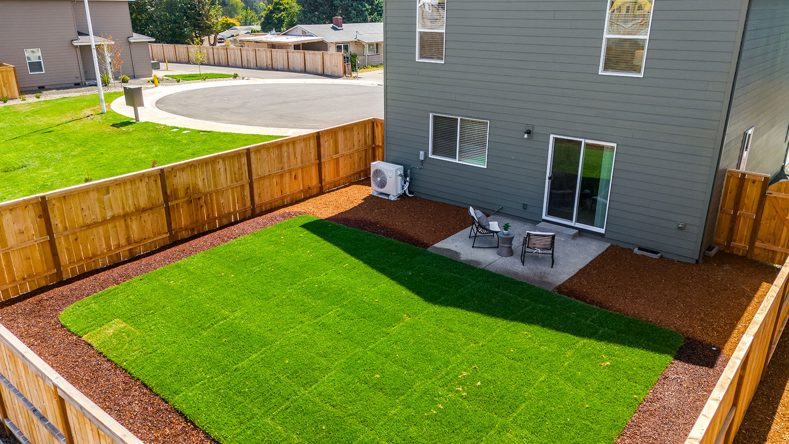fully fenced backyard with sod lawn and a patio