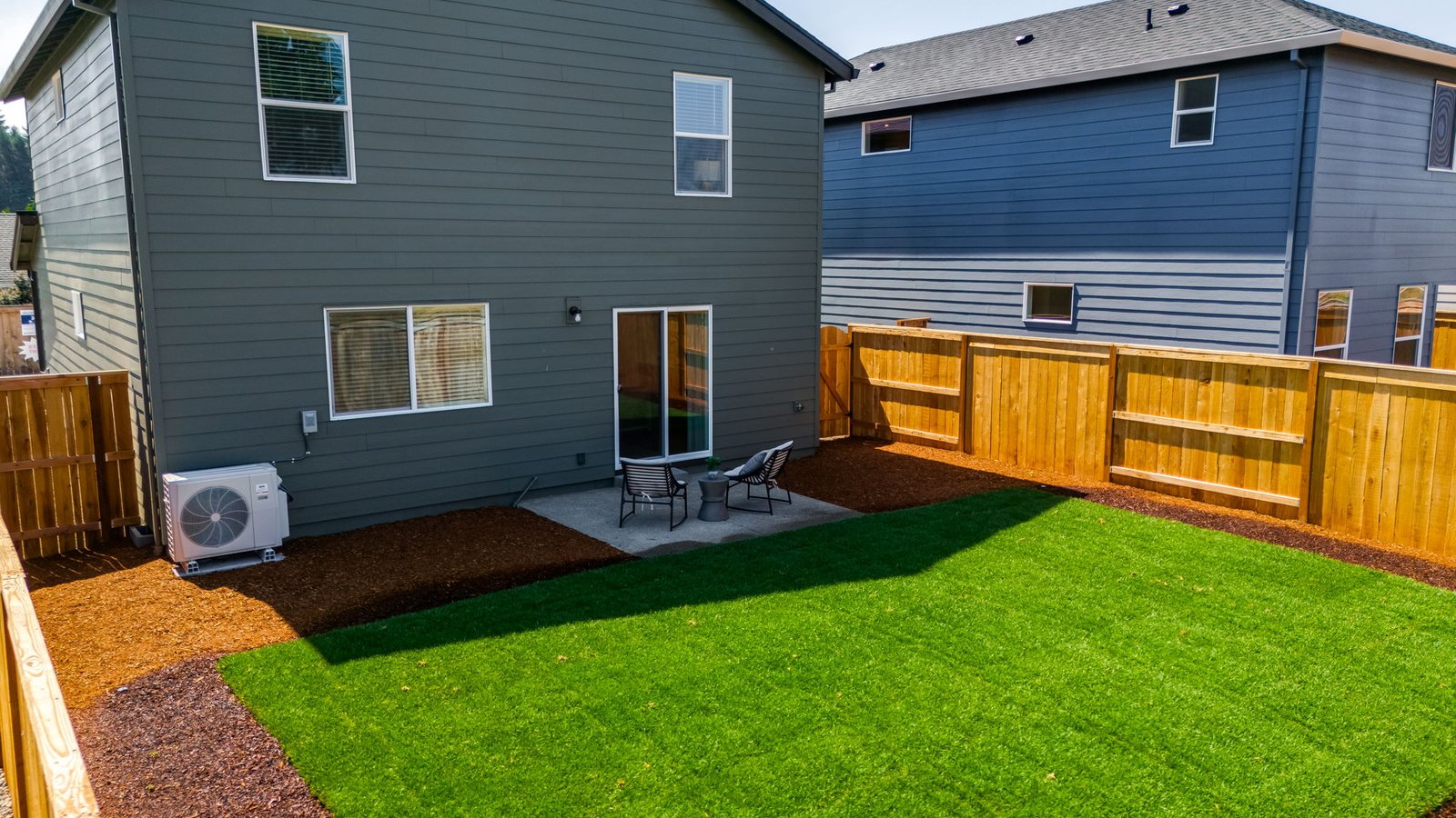fully fenced backyard with sod lawn and a patio