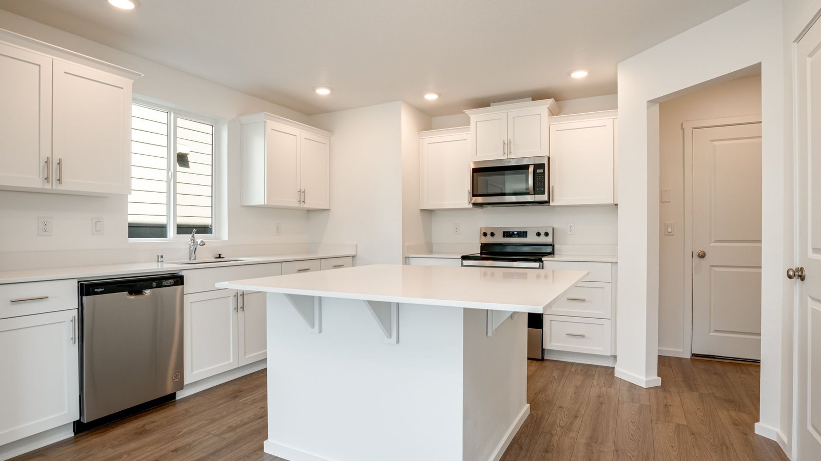 Kitchen with shaker cabinets, quartz counters, stainless steel appliances, pantry, and an island with a breakfast bar