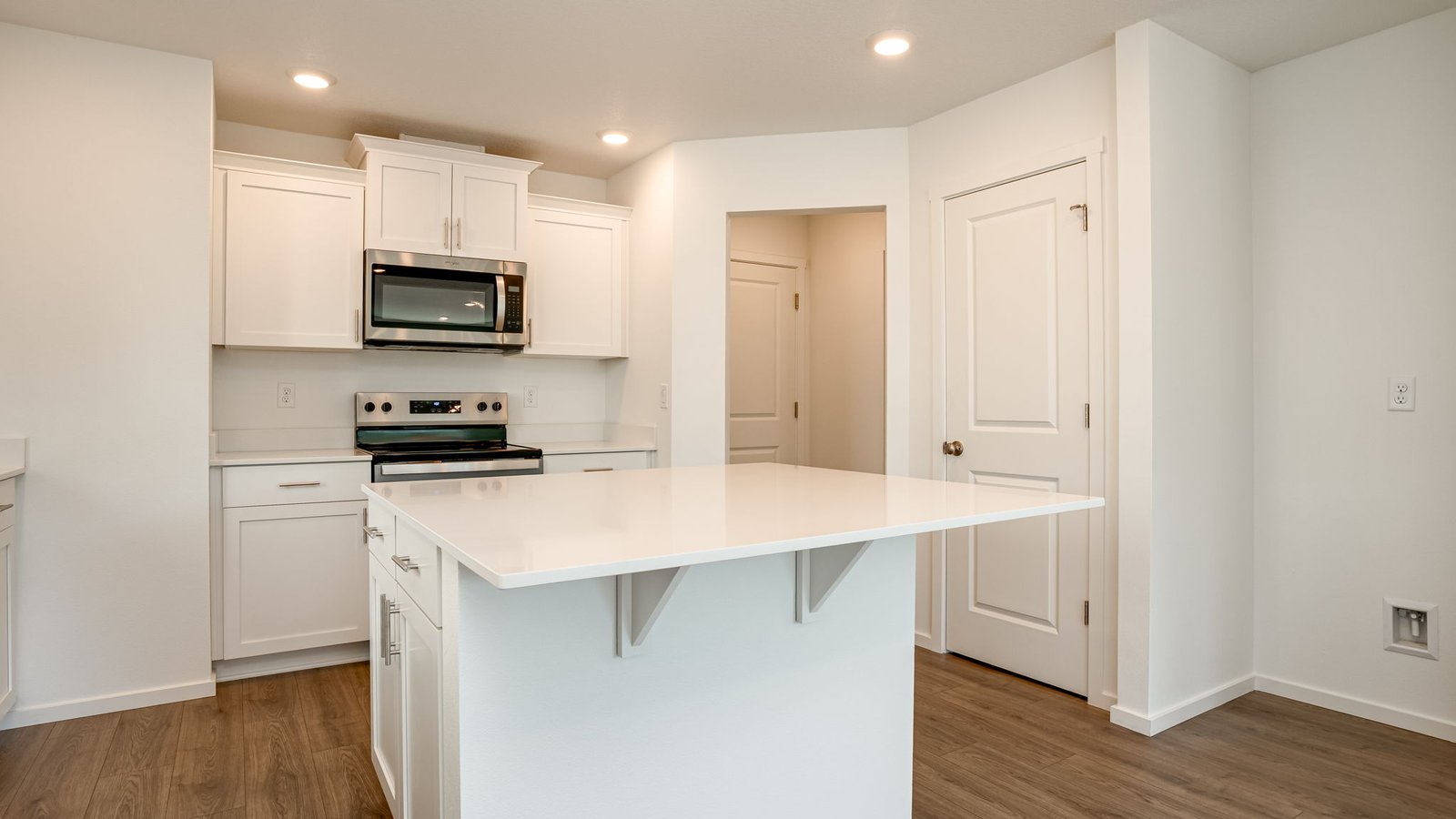Kitchen with shaker cabinets, quartz counters, stainless steel appliances, pantry, and an island with a breakfast bar