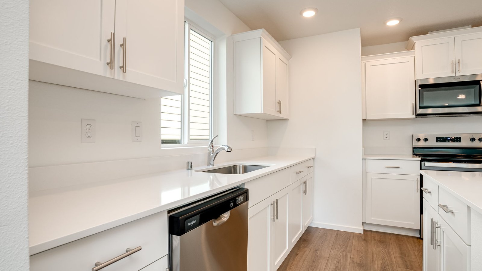Kitchen with shaker cabinets, quartz counters, stainless steel appliances, pantry, and an island with a breakfast bar
