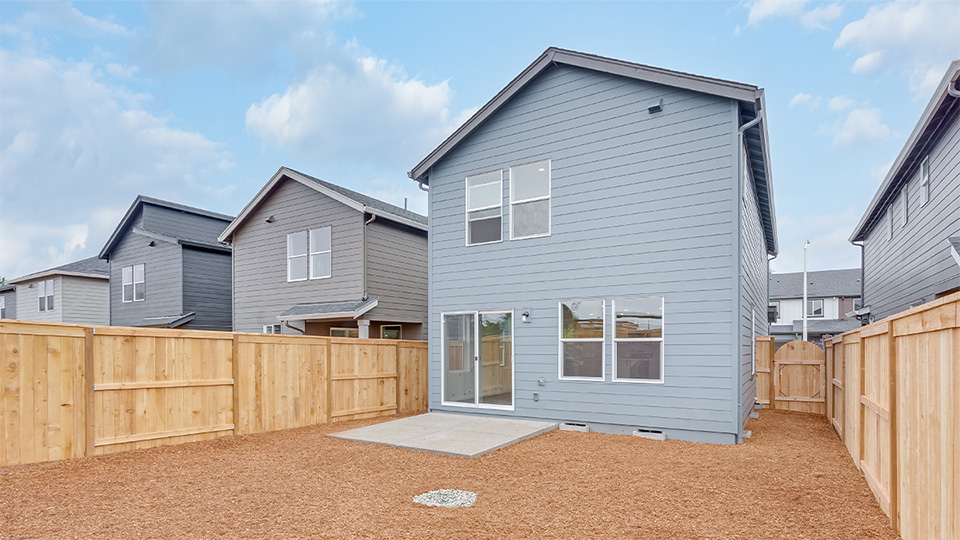 fully fenced backyard with bark chips and a patio