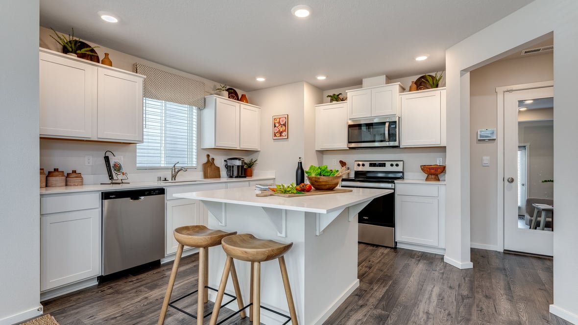 Kitchen with shaker cabinets, quartz counters, stainless steel appliances, pantry, and an island with a breakfast bar