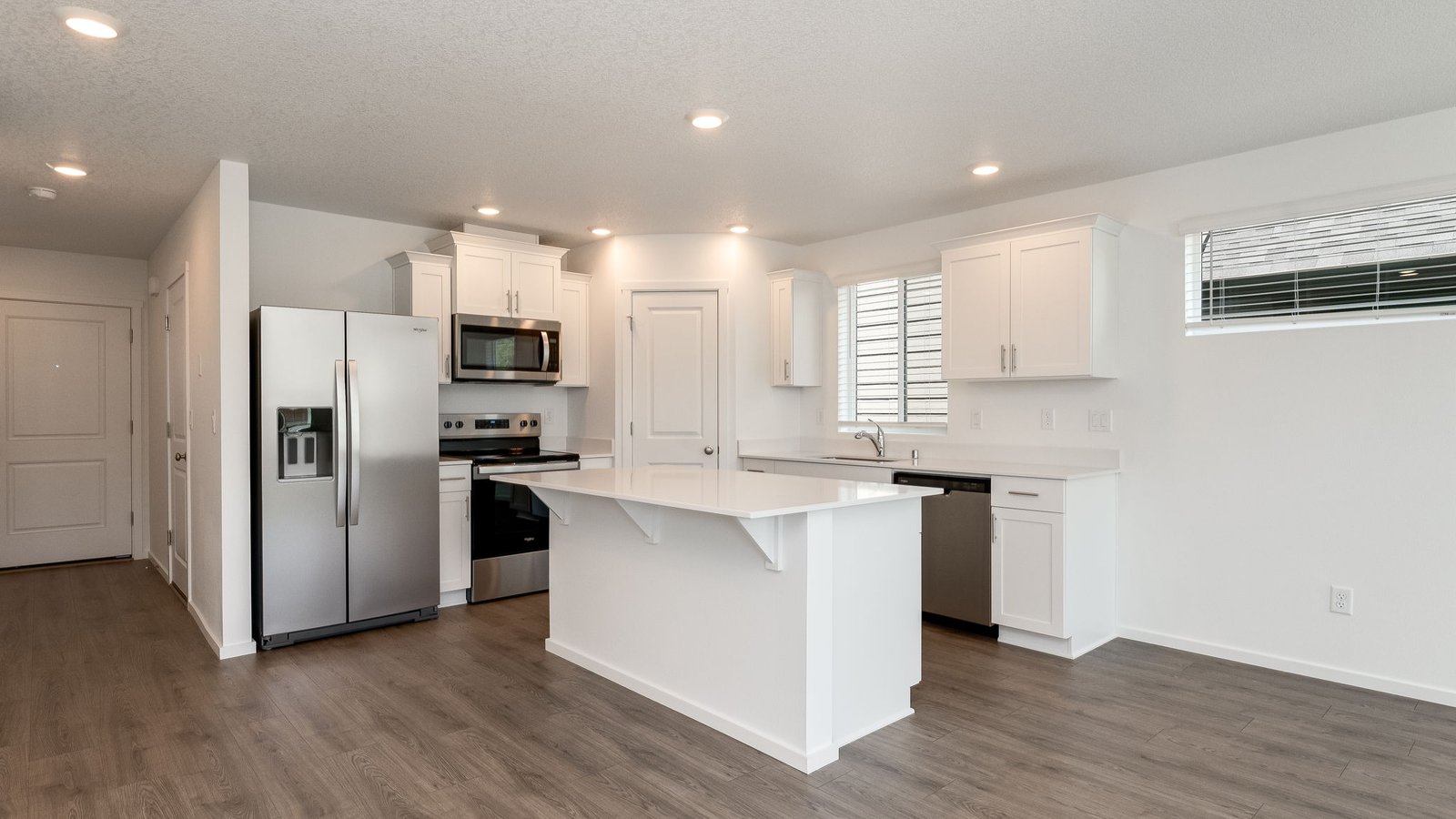 Kitchen with shaker cabinets, quartz counters, stainless steel appliances, pantry, and an island with a breakfast bar