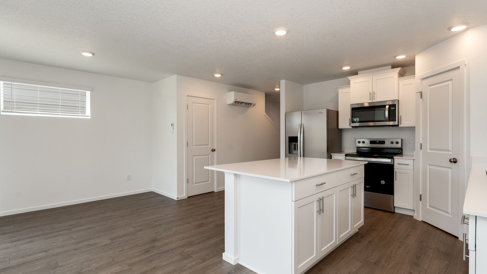Kitchen with shaker cabinets, quartz counters, stainless steel appliances, pantry, and an island with a breakfast bar