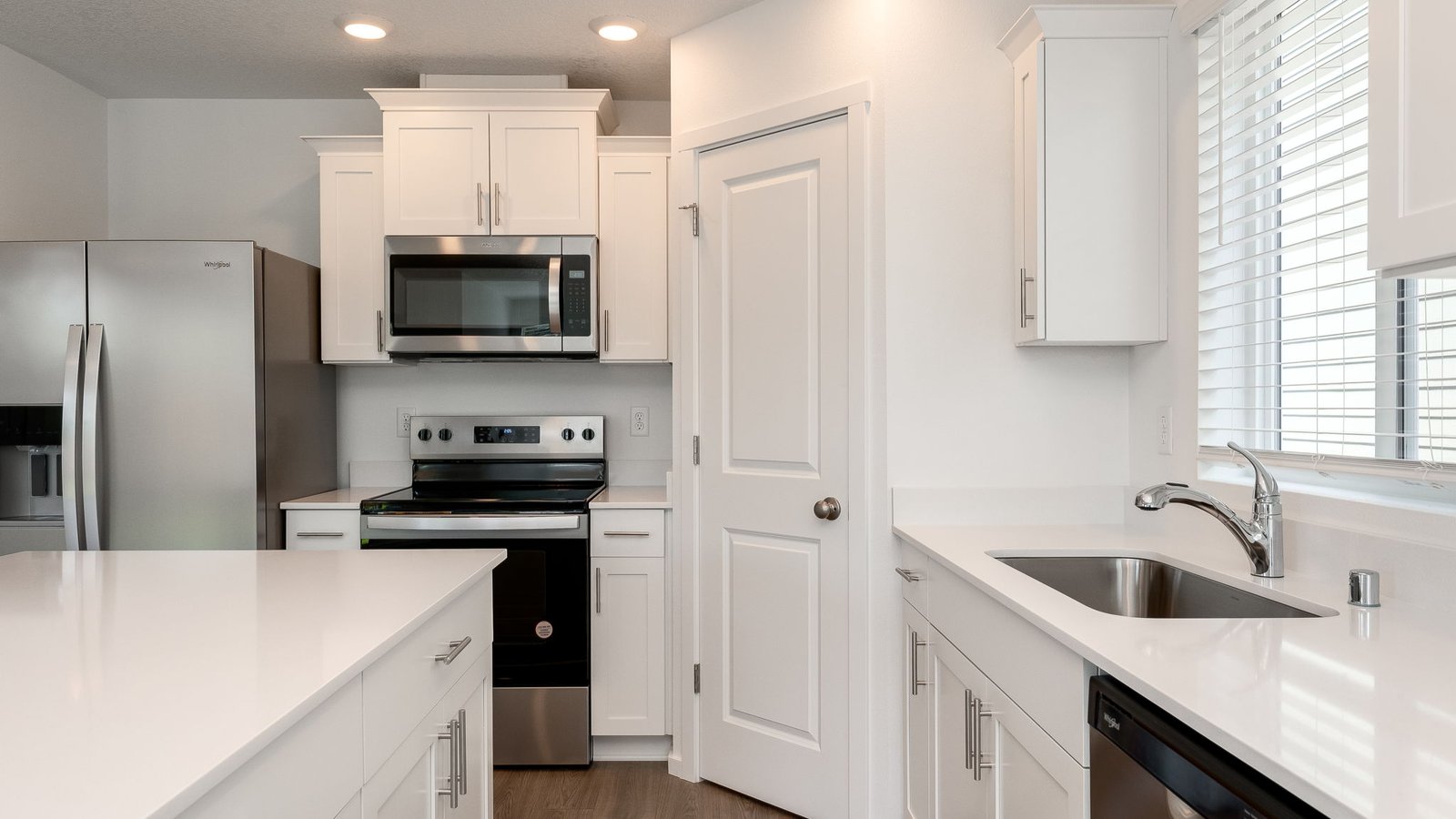 Kitchen with shaker cabinets, quartz counters, stainless steel appliances, pantry, and an island with a breakfast bar