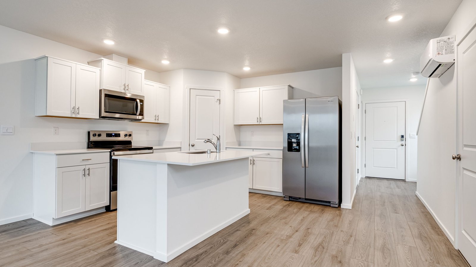 Kitchen with shaker cabinets, quartz counters, stainless steel appliances, pantry, and an island with a breakfast bar