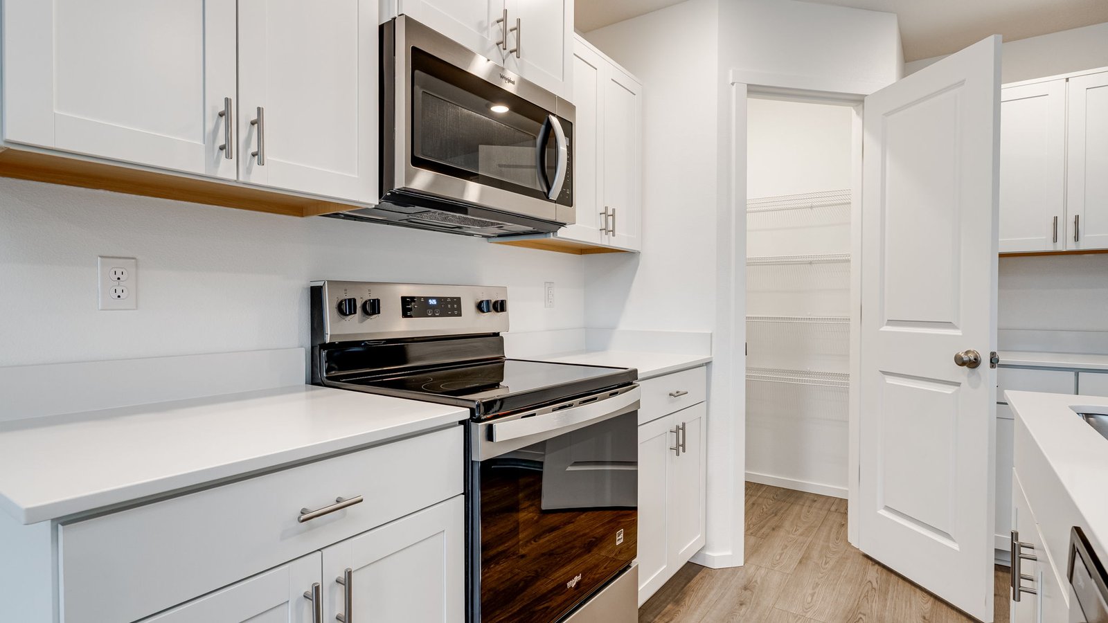Kitchen with shaker cabinets, quartz counters, stainless steel appliances, pantry, and an island with a breakfast bar