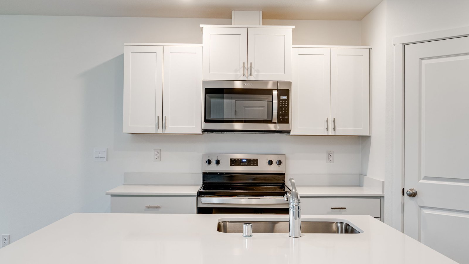 Kitchen with shaker cabinets, quartz counters, stainless steel appliances, pantry, and an island with a breakfast bar