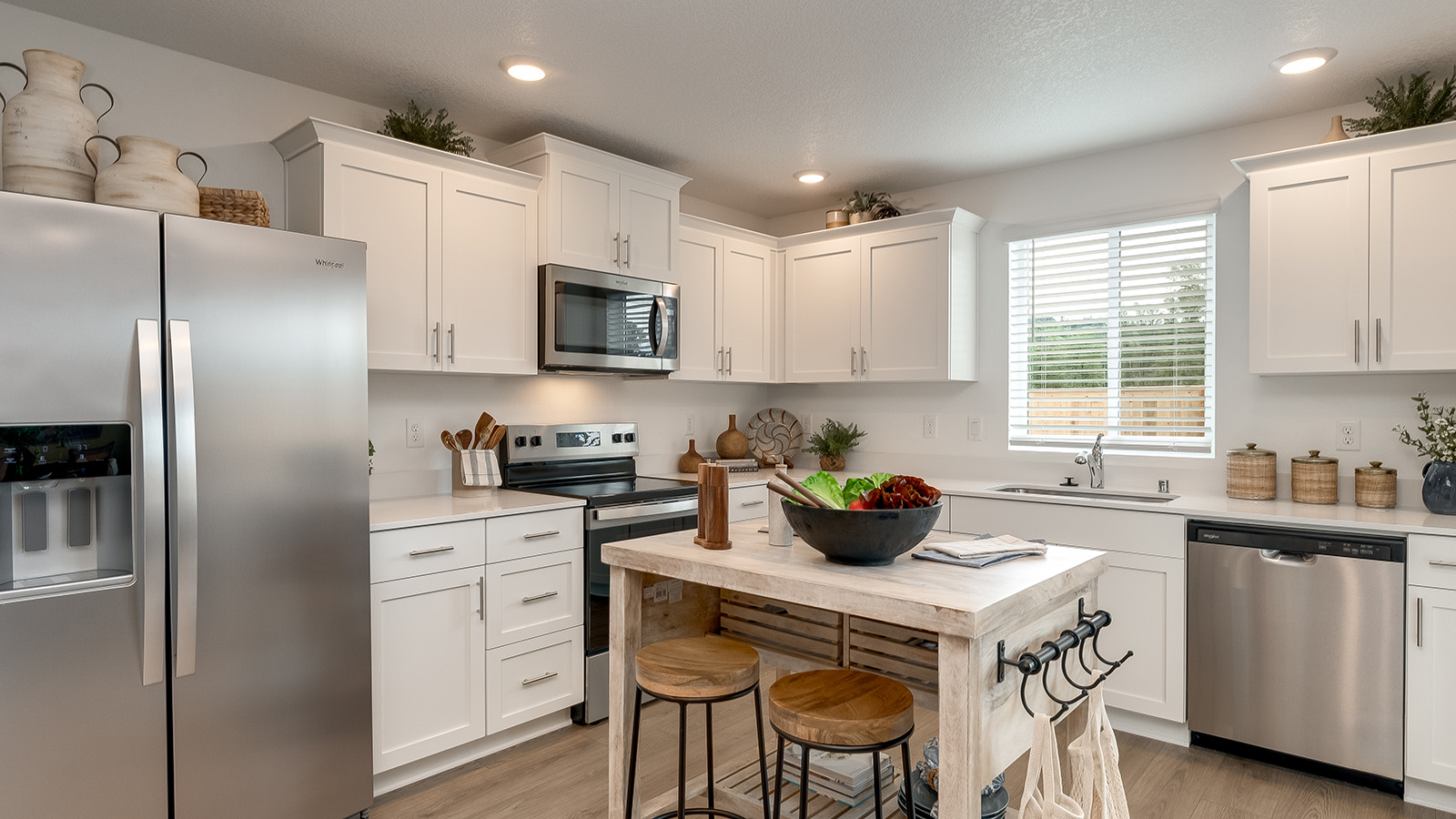 L-shaped kitchen with shaker cabinets, quartz counters, stainless steel appliances, and a pantry