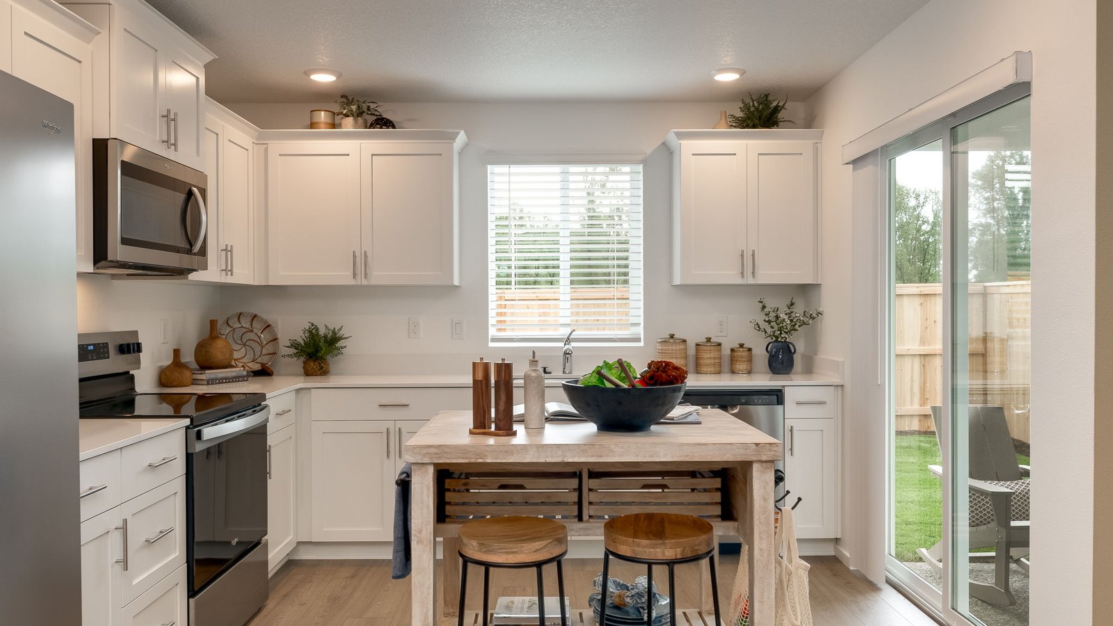 L-shaped kitchen with shaker cabinets, quartz counters, stainless steel appliances, and a pantry