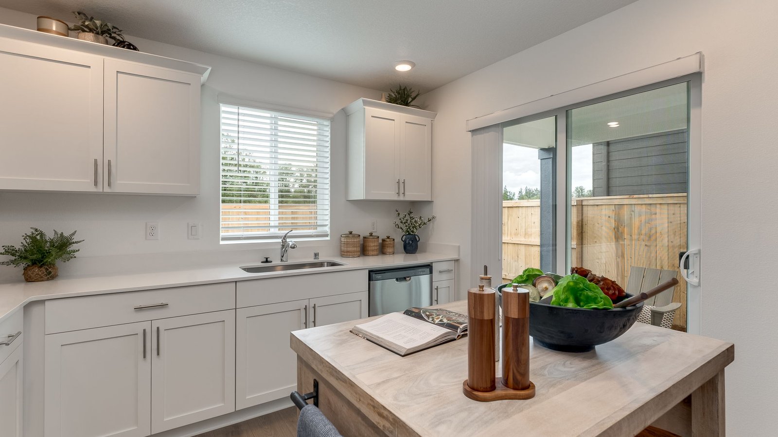 L-shaped kitchen with shaker cabinets, quartz counters, stainless steel appliances, and a pantry
