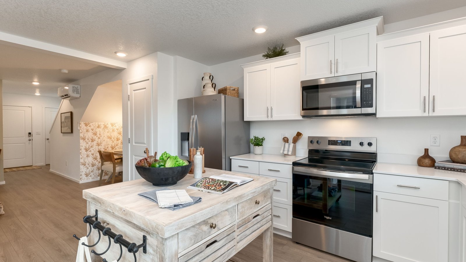 L-shaped kitchen with shaker cabinets, quartz counters, stainless steel appliances, and a pantry