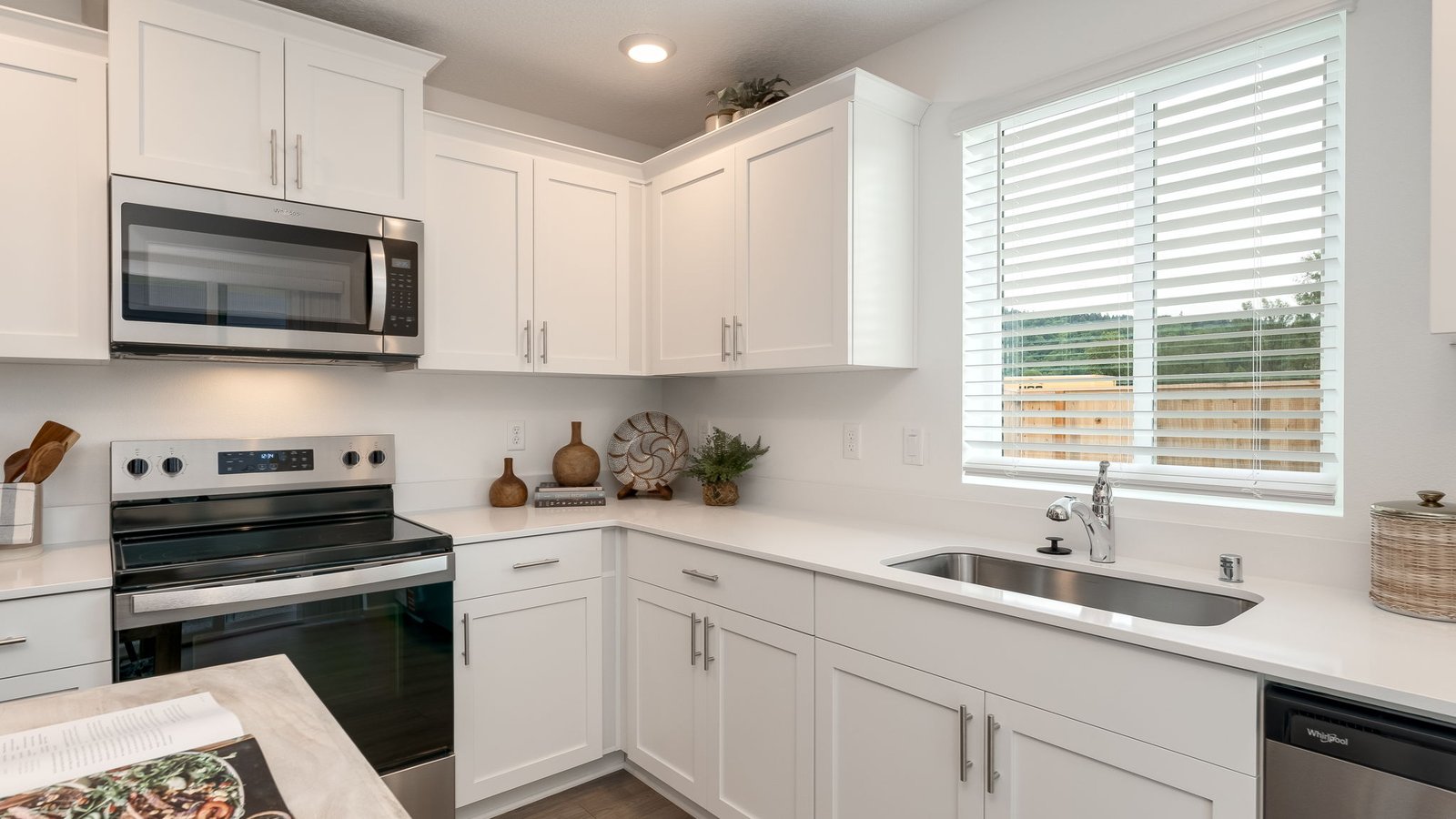 L-shaped kitchen with shaker cabinets, quartz counters, stainless steel appliances, and a pantry