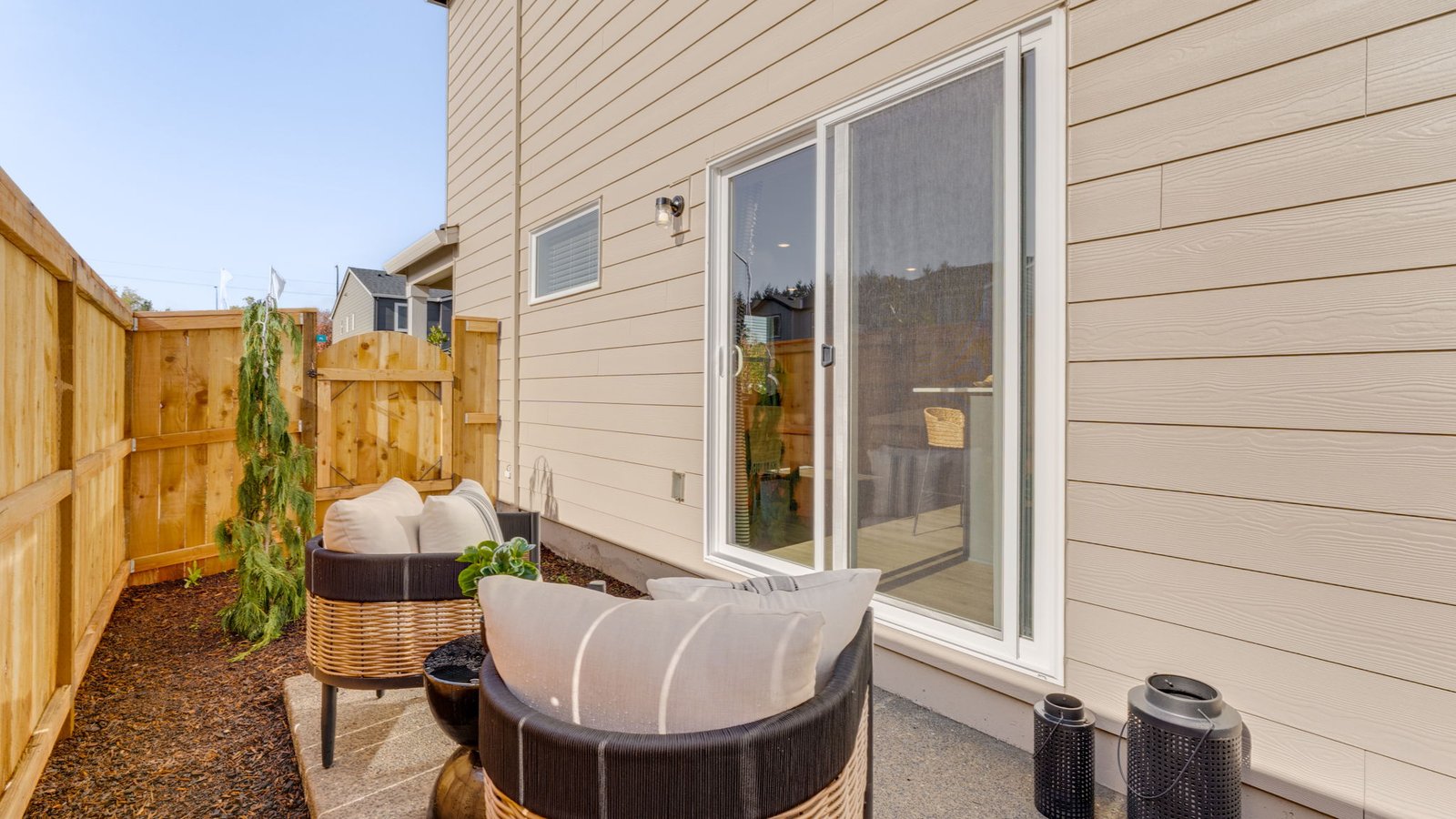 fully fenced sideyard with bark chips and a patio
