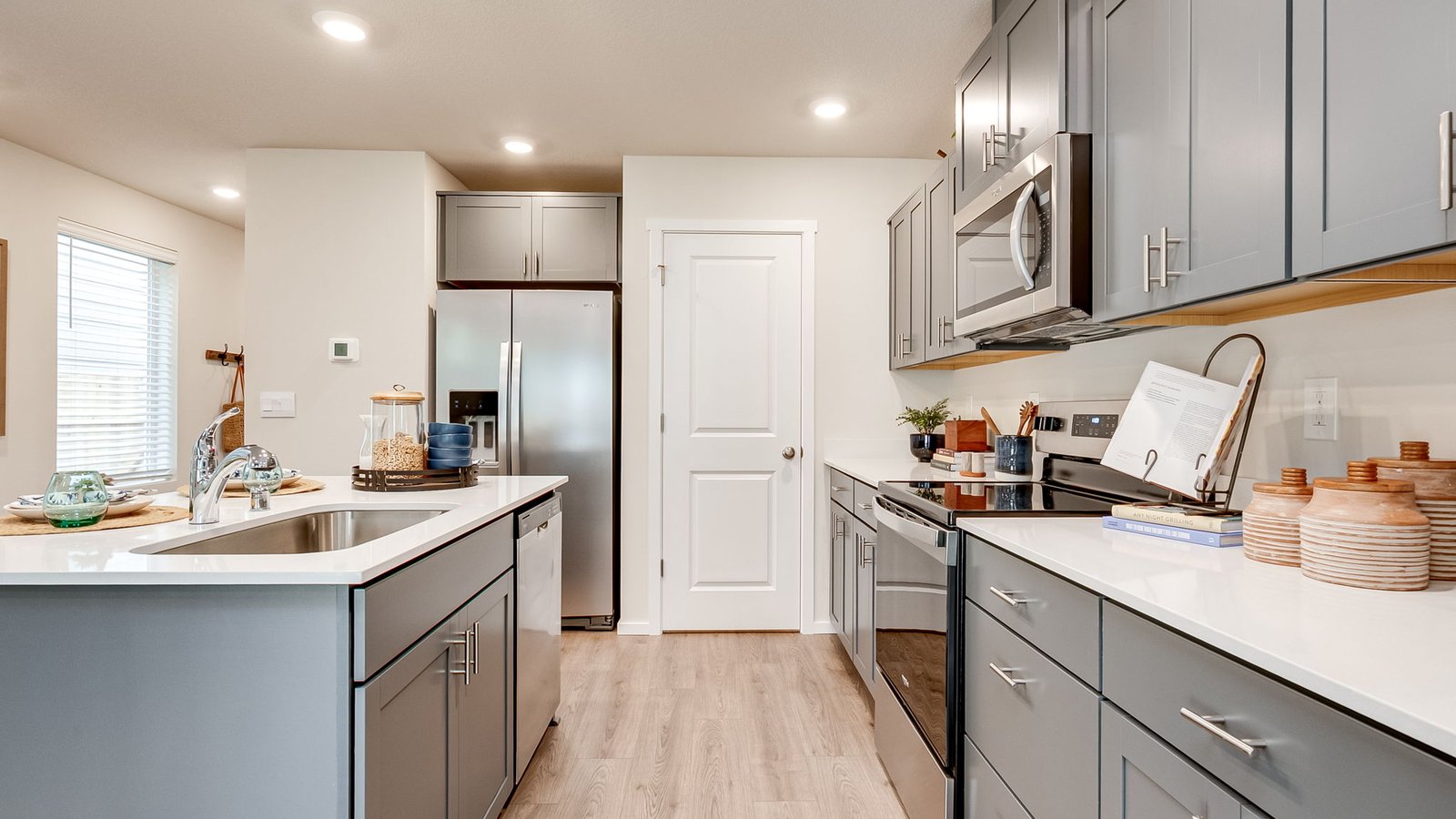 Kitchen with shaker cabinets, quartz counters, stainless steel appliances, pantry, and an island with a breakfast bar