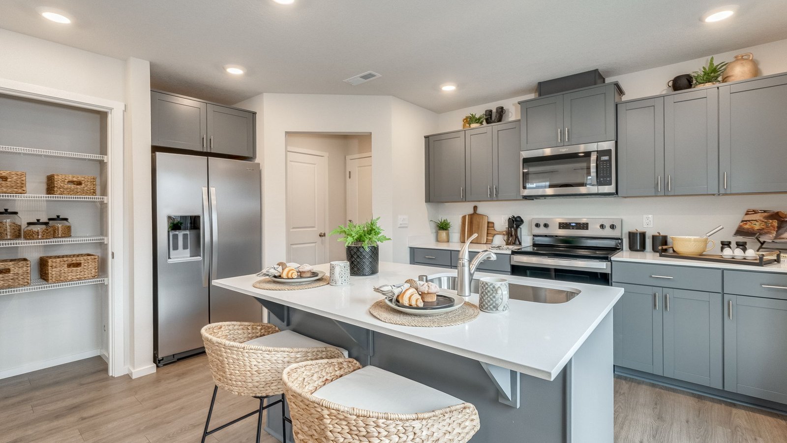 Kitchen with shaker cabinets, quartz counters, stainless steel appliances, pantry, and an island with a breakfast bar