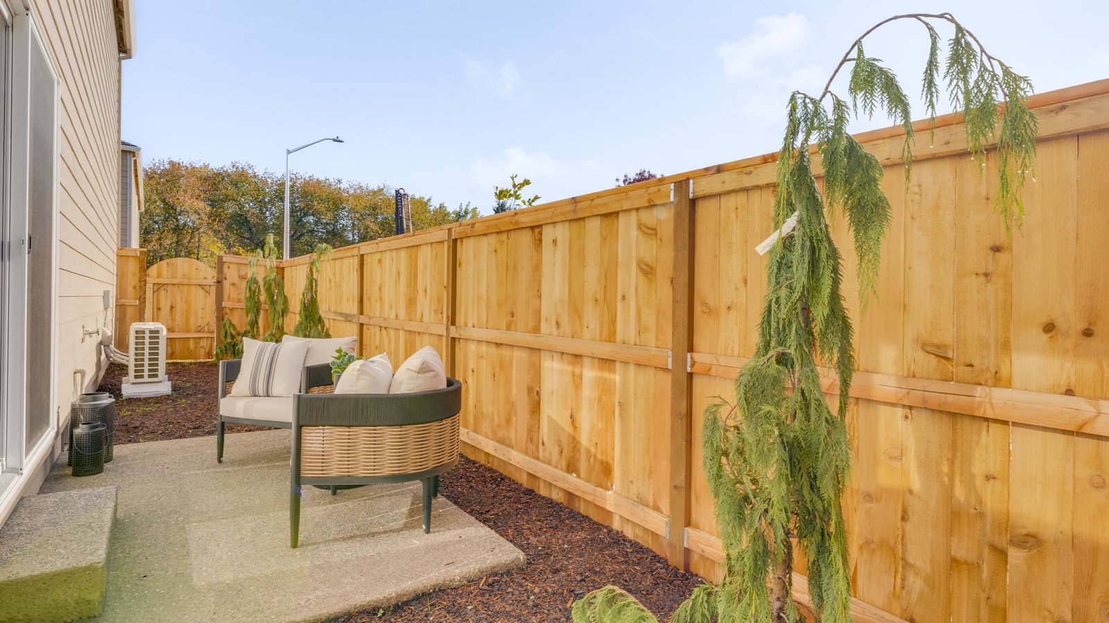 fully fenced sideyard with bark chips and a patio